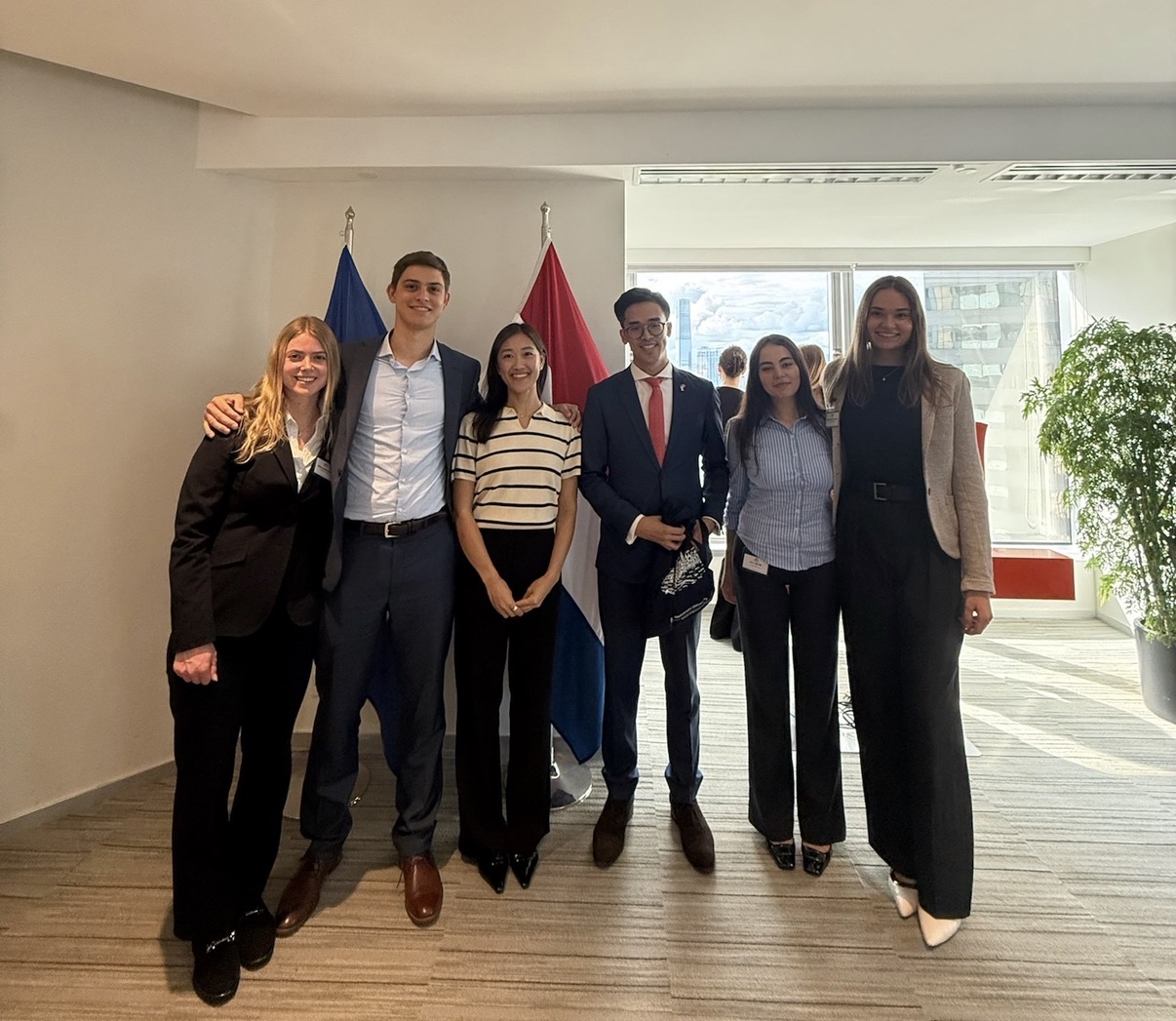 Six students standing in front of the Dutch flag in a consulate reception room in Hong Kong