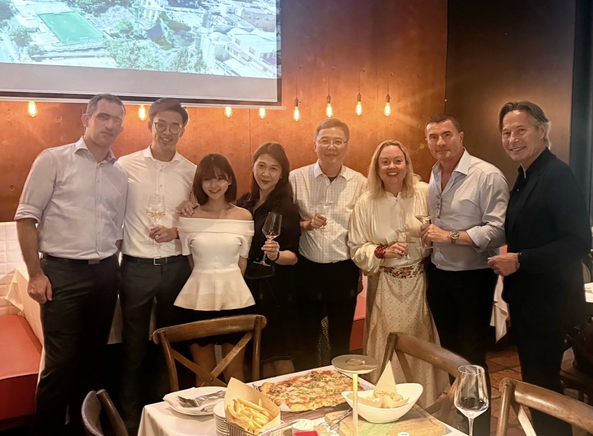 Nine guests with drinks standing behind a restaurant table at a Dutch Chamber networking cocktail